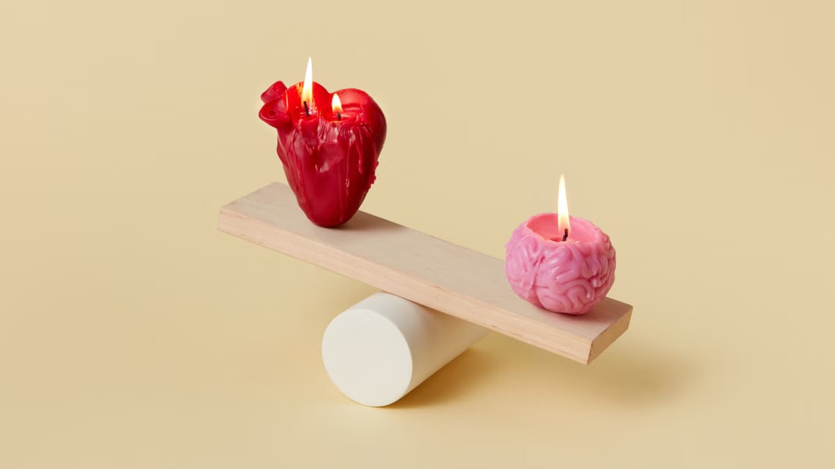 Artistic balance of heart-shaped and brain-shaped candles on a seesaw for conceptual representation.